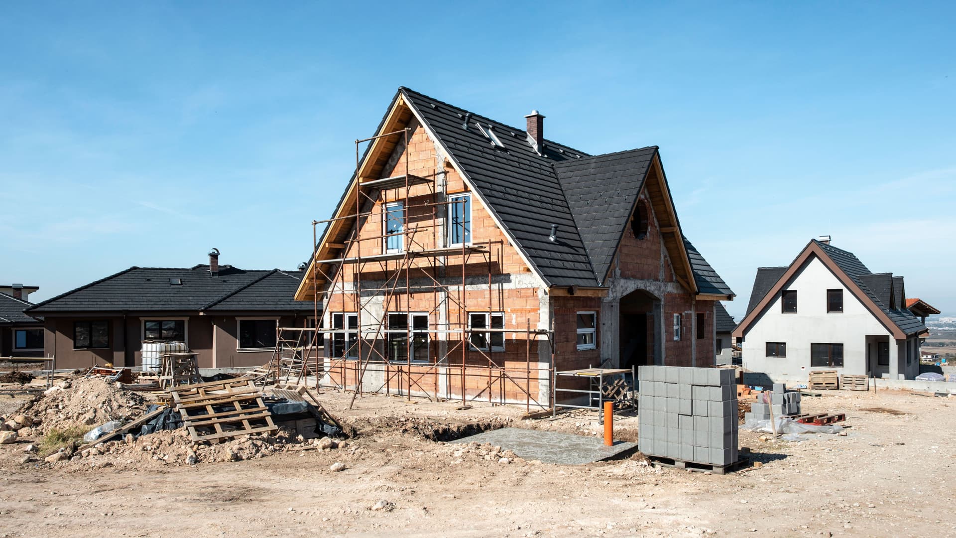 Ein Einfamilienhaus in einer Neubausiedlung. Es ist eingerüstet.