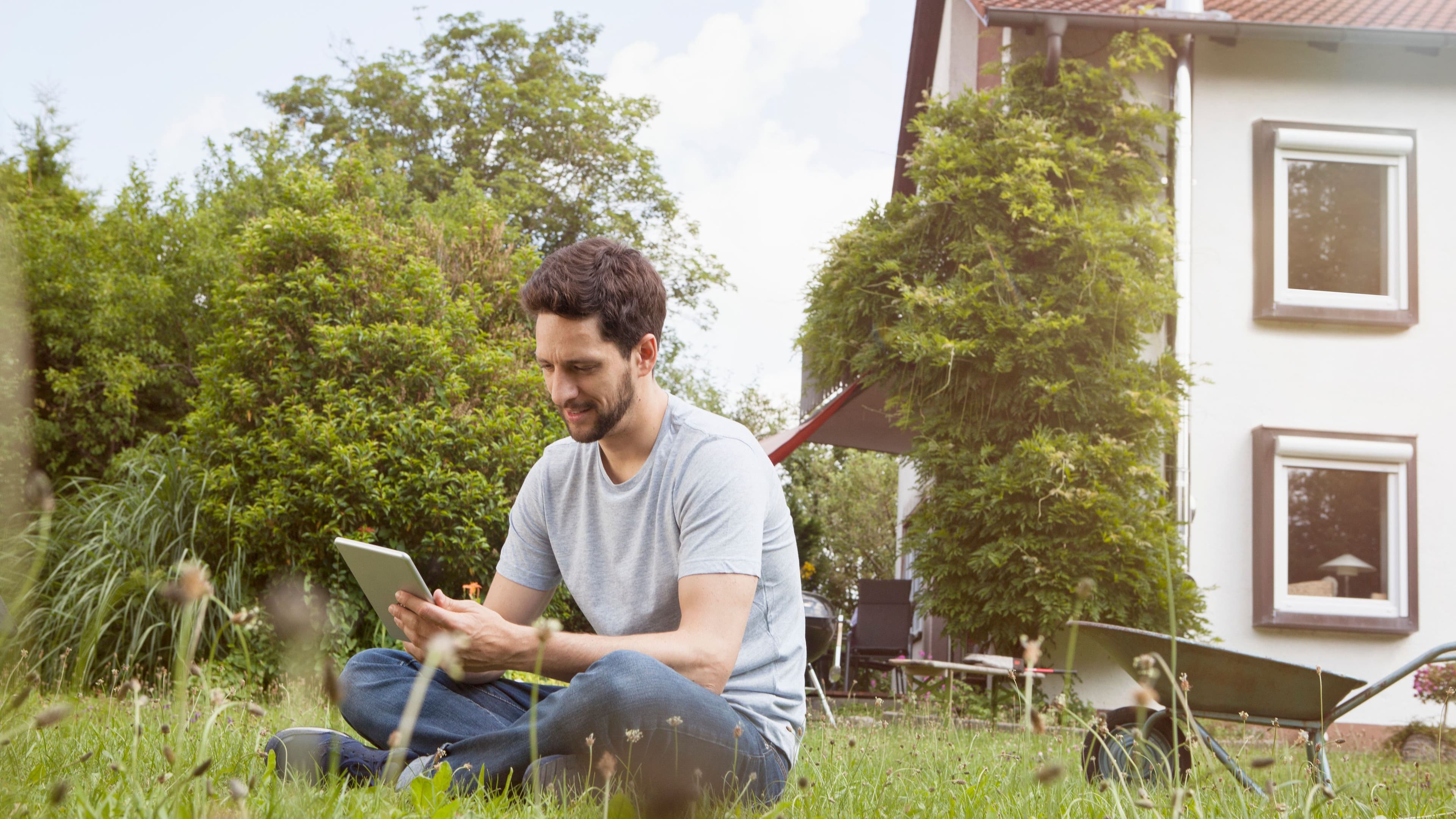 Man sitting in garden using digital tablet