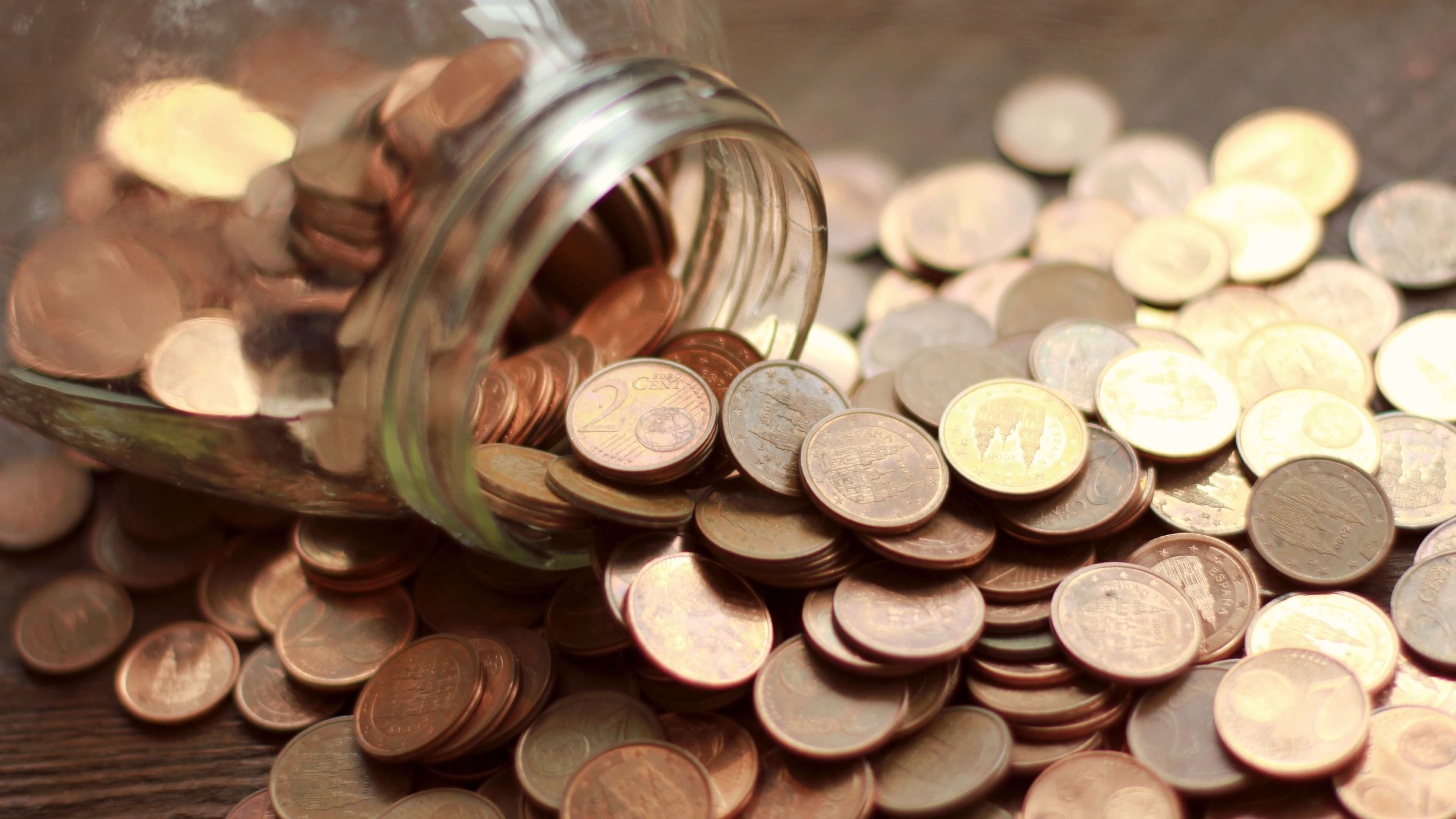 Glas mit ausgeschütteten Eurocent Münzen auf einem Tisch