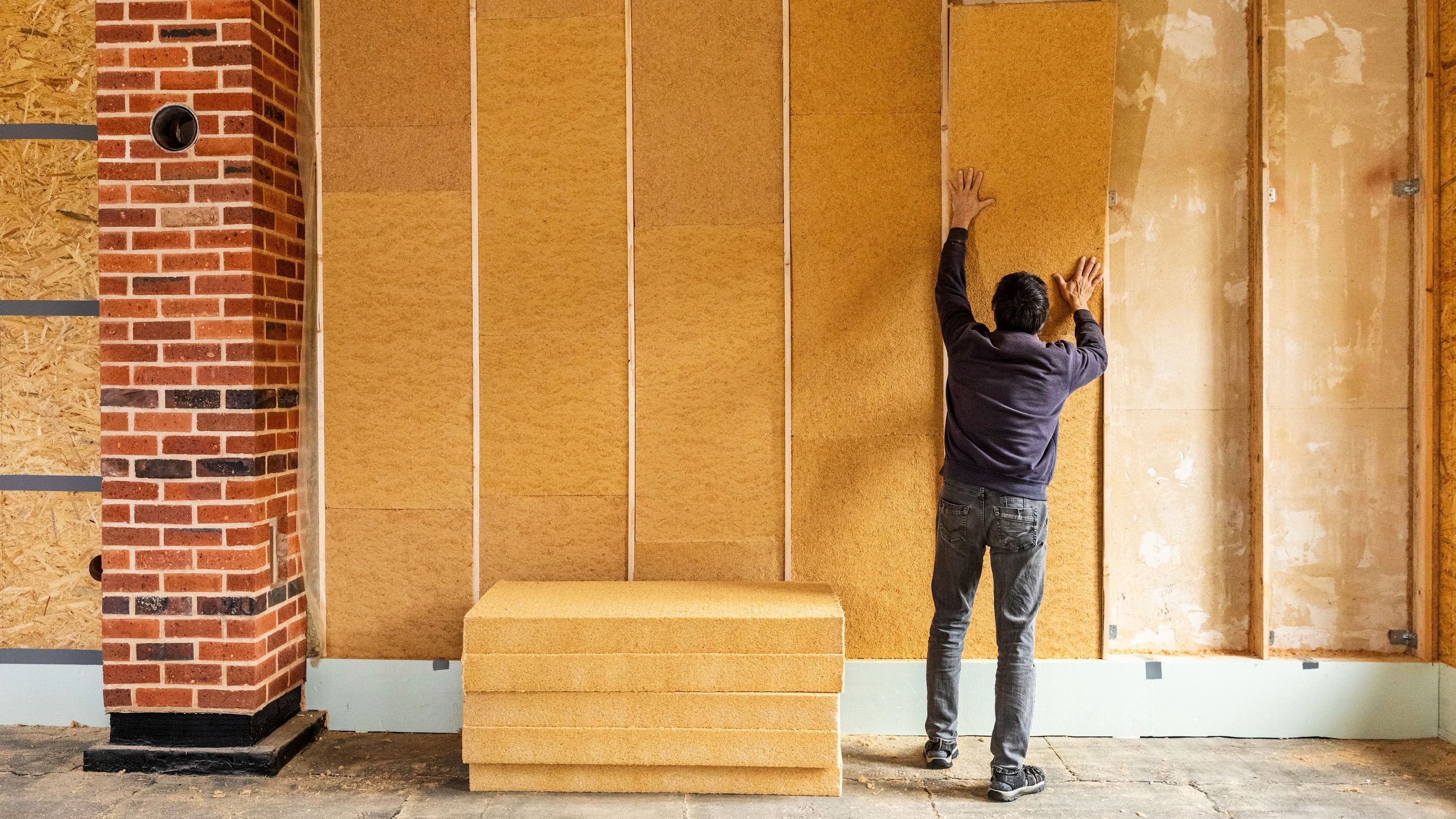 Ein Mann baut eine Wärmedämmung in eine Wand ein.