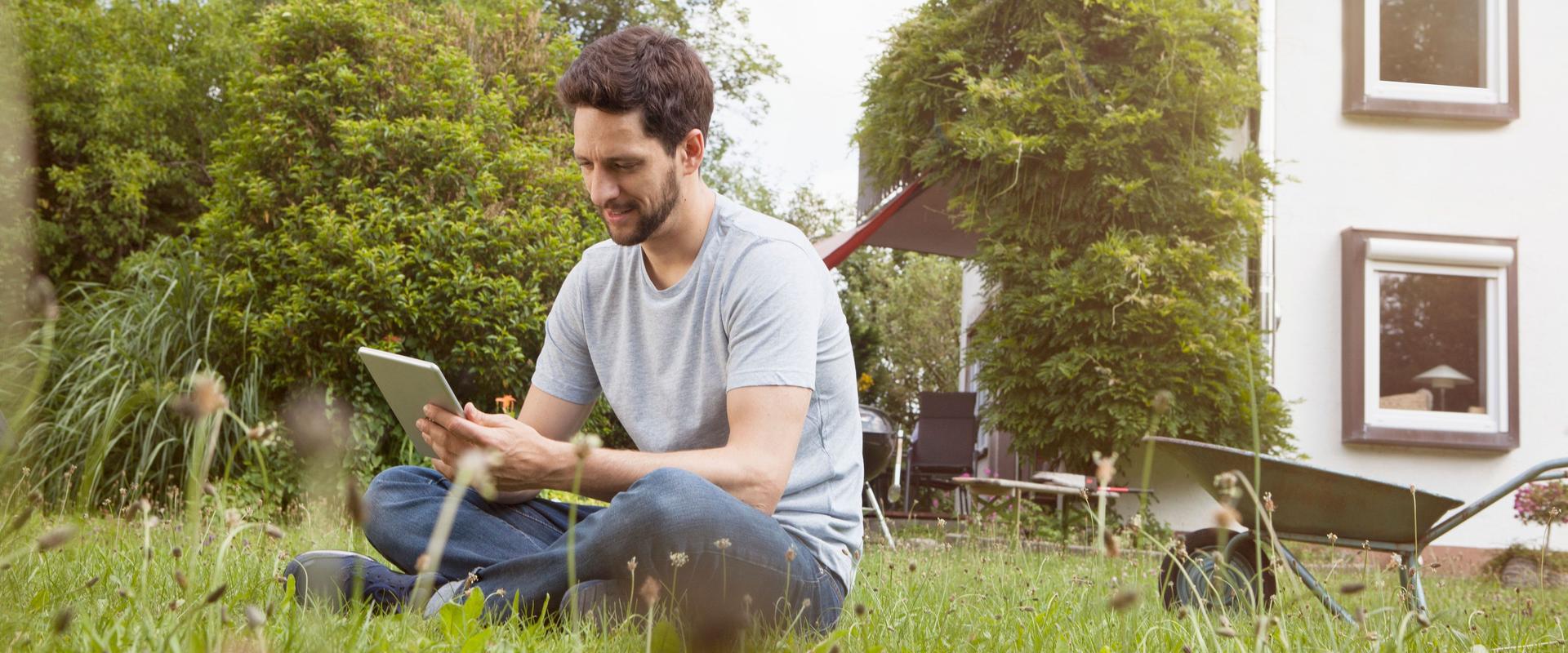 Man sitting in garden using digital tablet