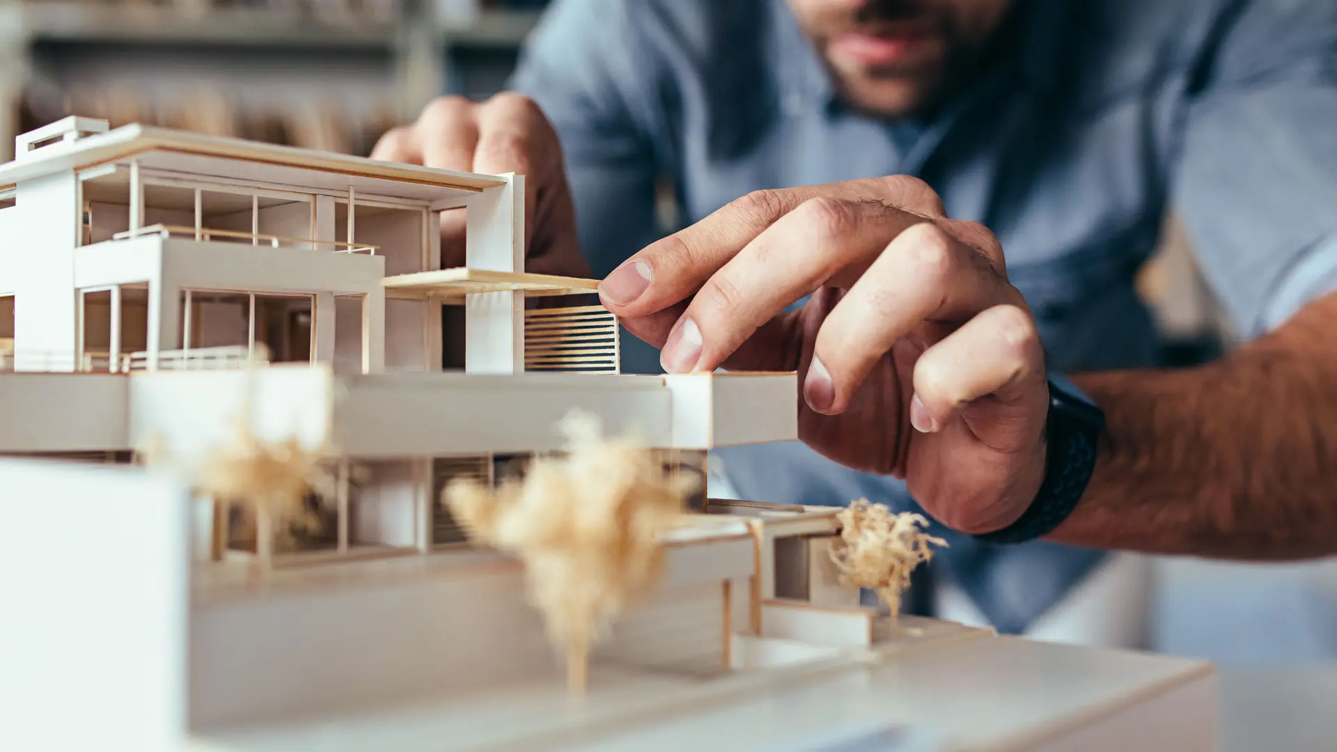 Ein Architekturmodell eines Hauses wird per Hand bearbeitet